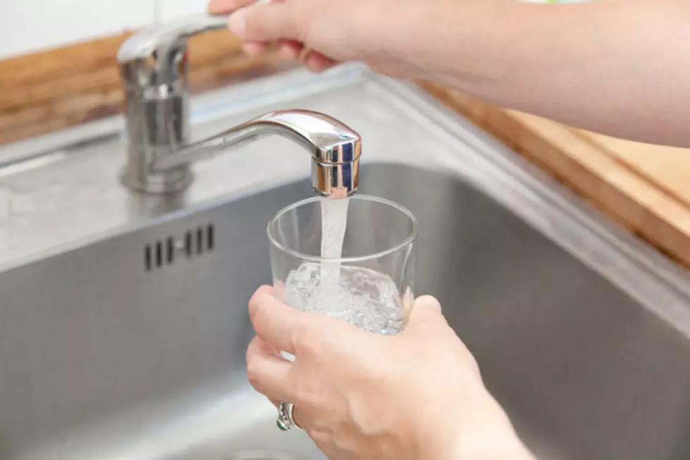 woman holding glass at water tap and filling water.